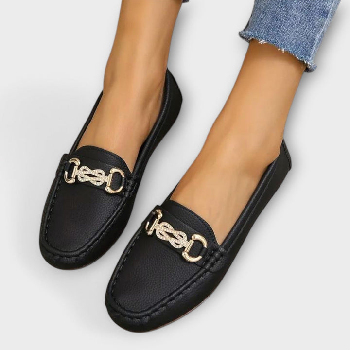 Μαύρα loafers με ανάγλυφο δέρμα και μεταλλική αγκράφα στο μπροστινό μέρος.